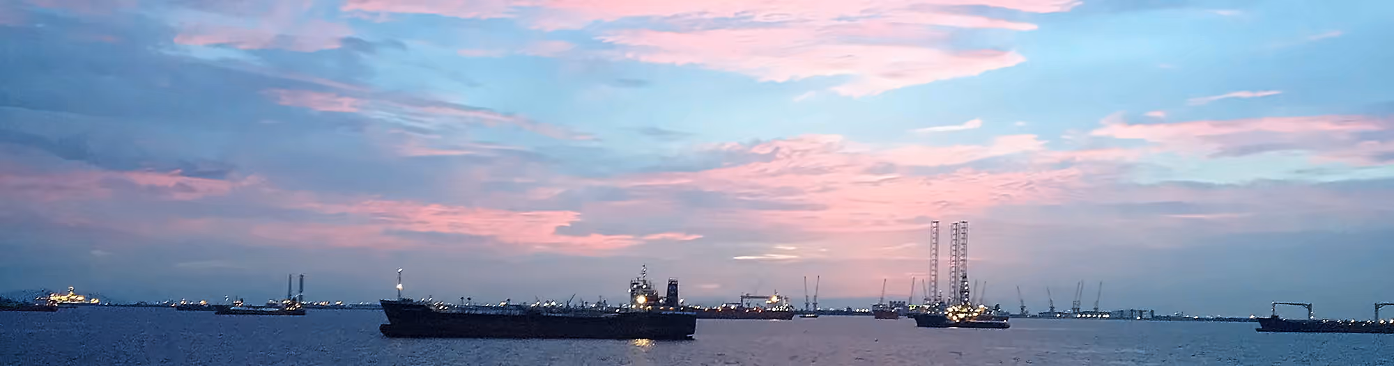 Vessels and a jack-up rig at anchor off Singapore at dusk